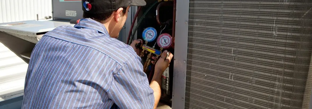 HVAC technician servicing a condenser unit in South Williamsport